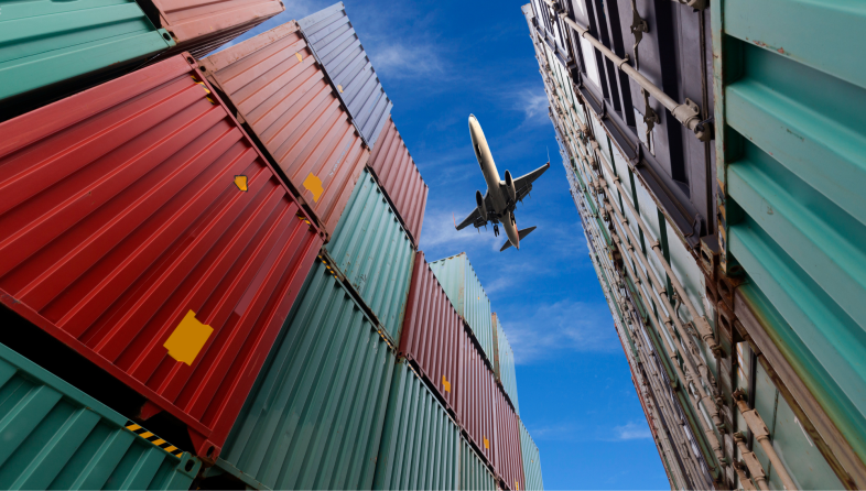 Airplane flying over shipping containers