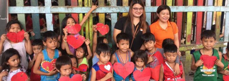 EFL staff with children holding red paper hearts